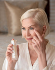 Woman applying skincare product in a bedroom setting