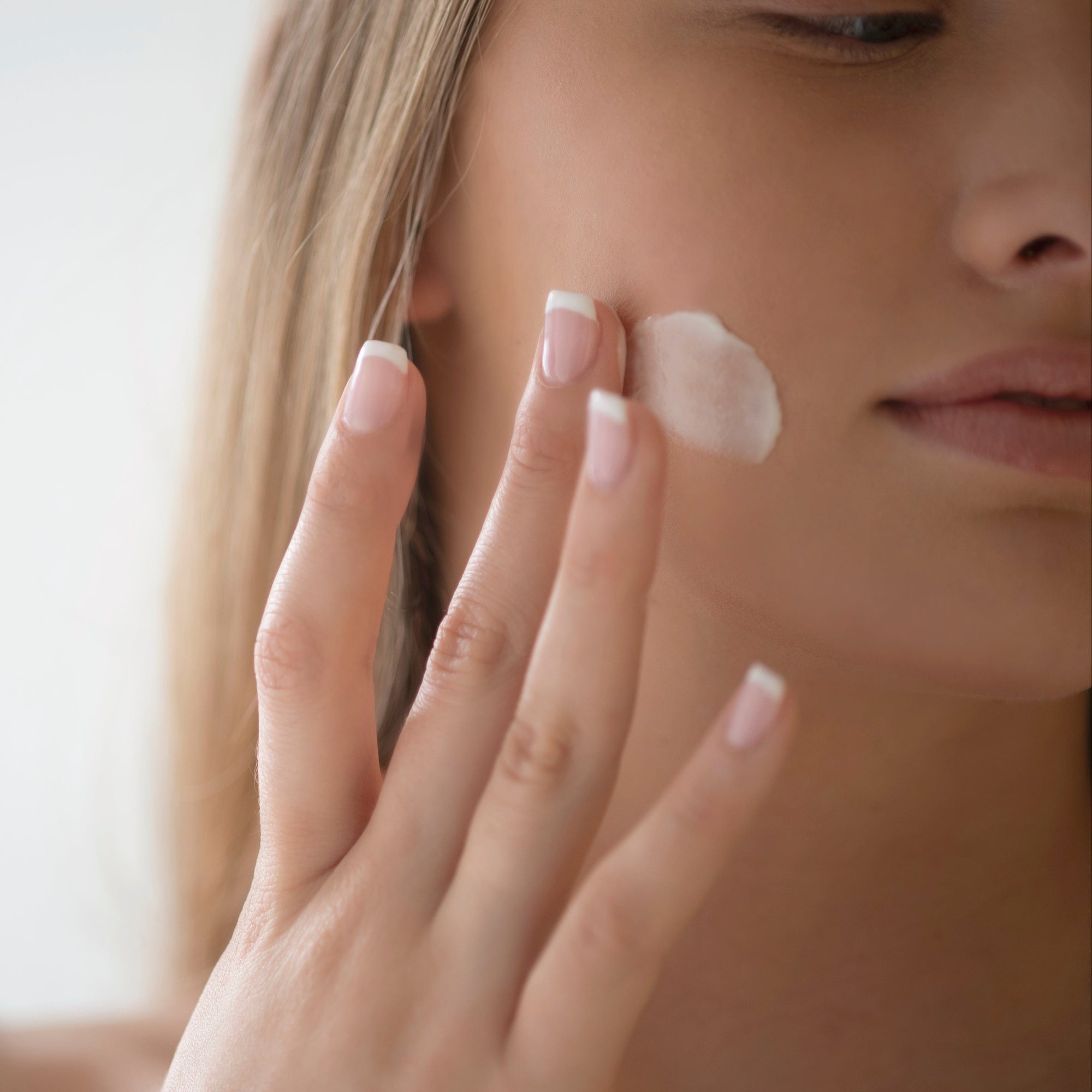 Model applying Sapelo Rejuvenating Cream – anti-aging moisturizer with peptides and botanicals to firm and restore skin