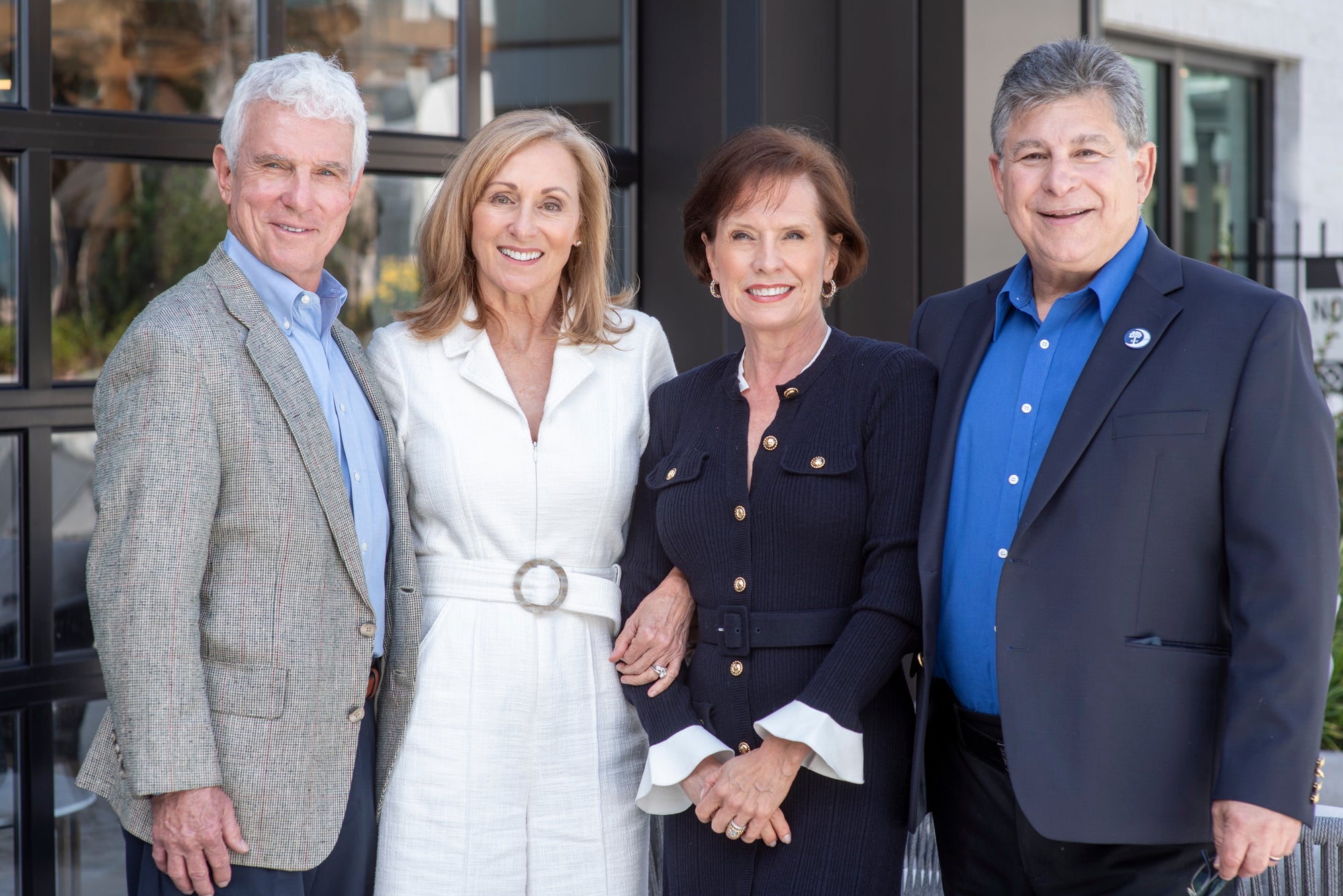 Four people posing together in front of a building