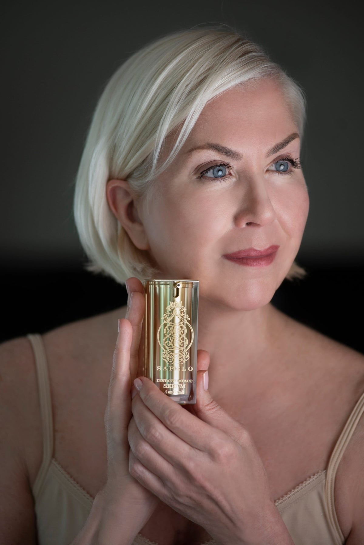 Woman holding a gold and black cylindrical product against a dark background