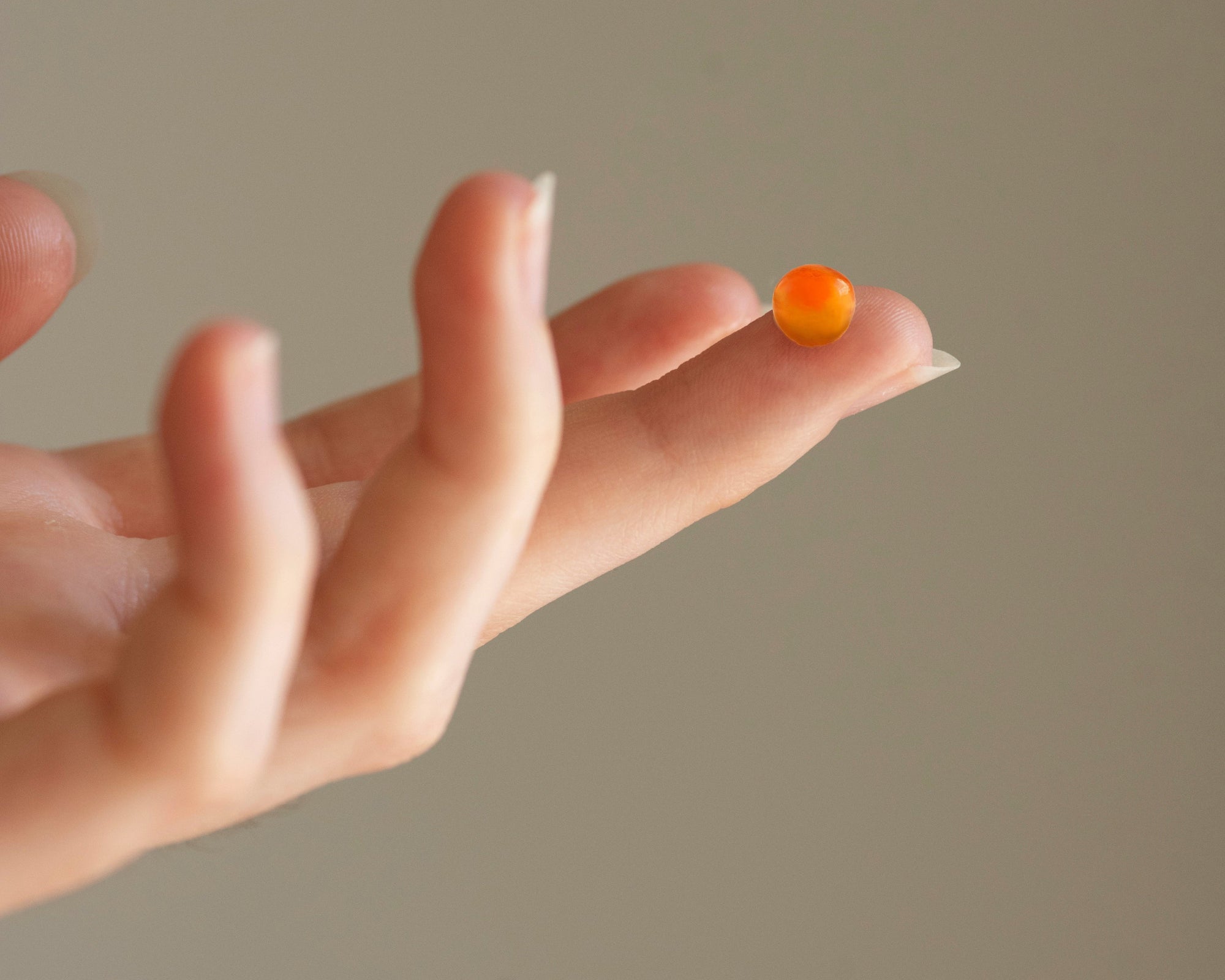 Hand holding a small caviar egg 