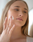 Woman applying cream to her face with a blurred background