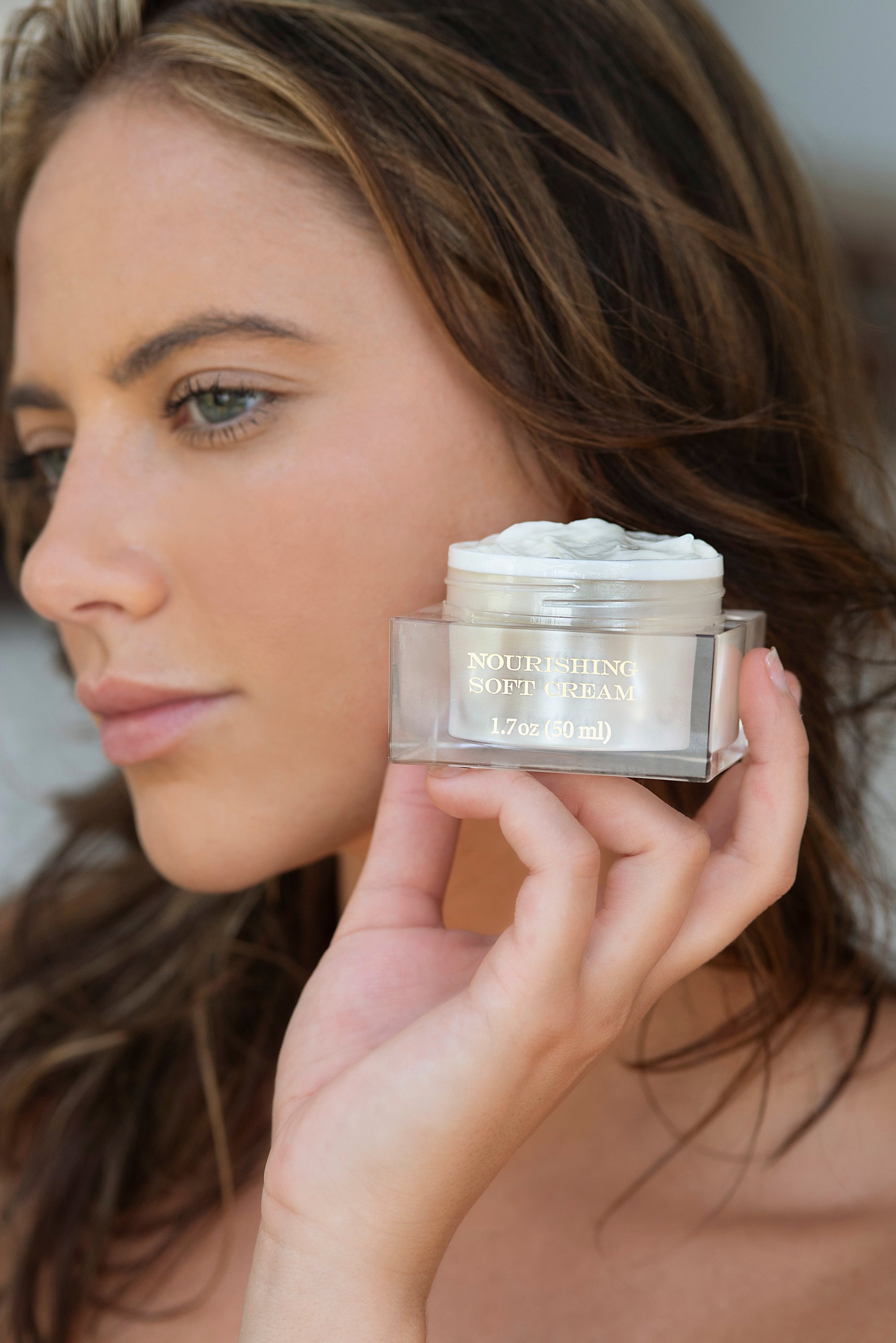 Woman holding a jar of skincare cream close to her face