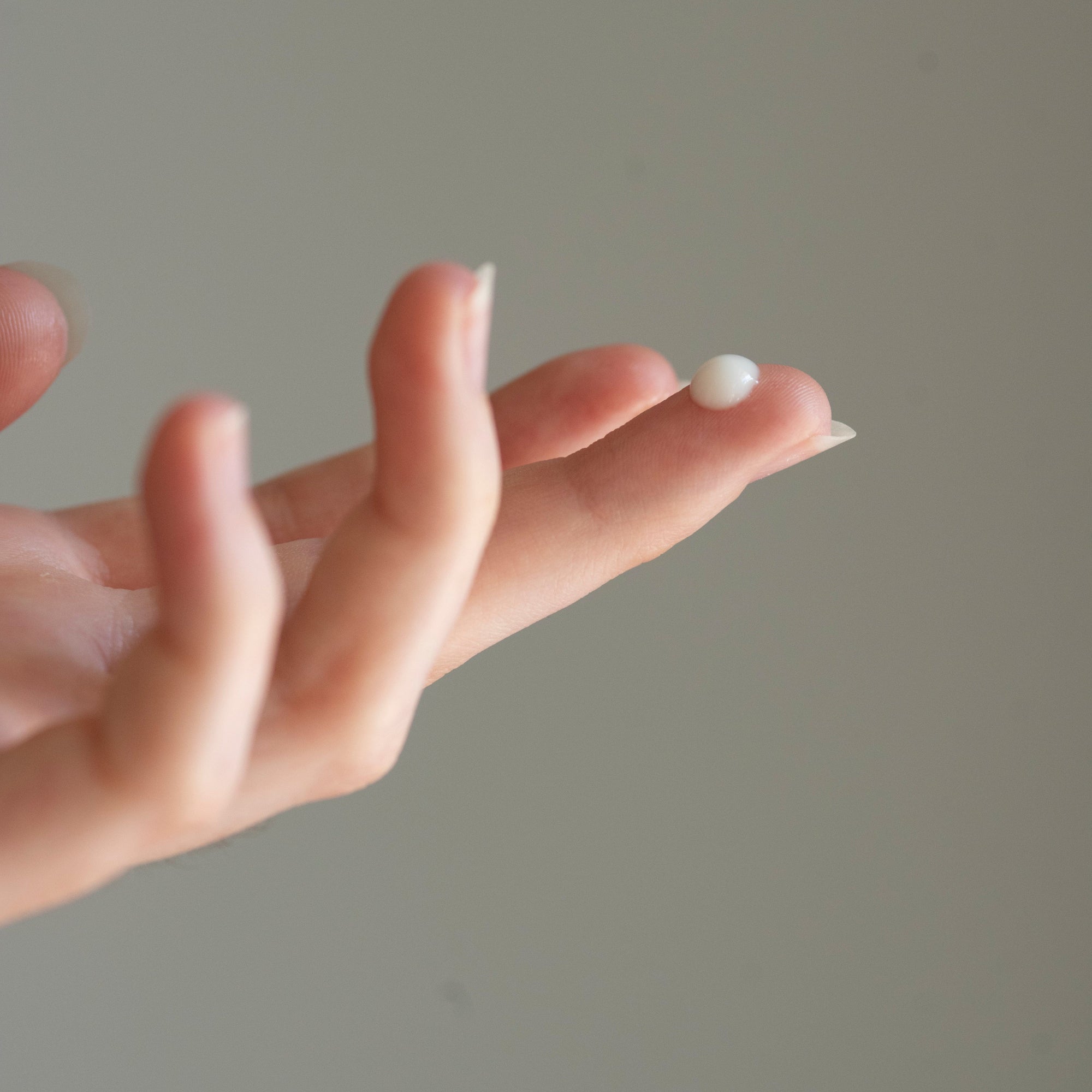 Model with Sapelo Skin Care Spring Tide Anti Aging Serum on tip of finger 