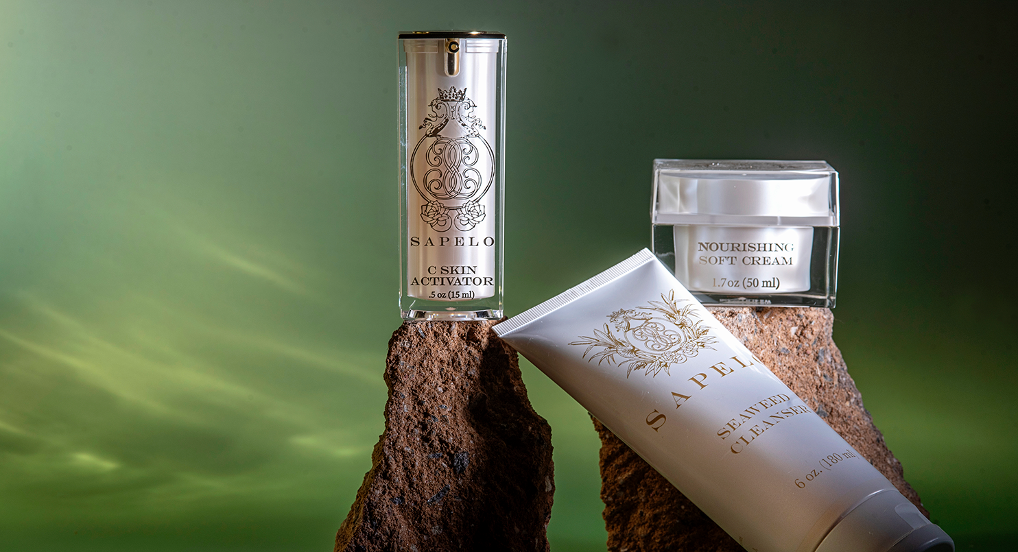 Skincare products on a natural stone surface with a green gradient background