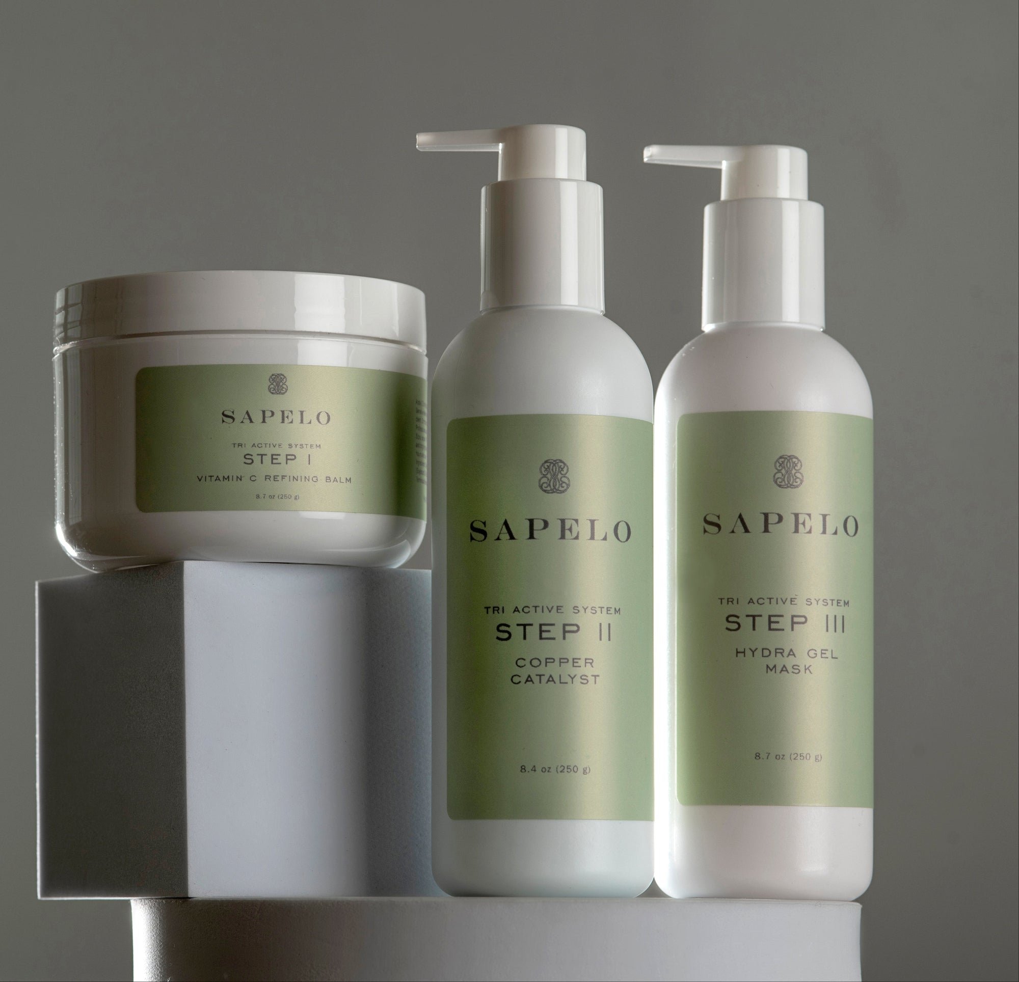 Sapelo skincare products including a jar and two bottles on a gray background