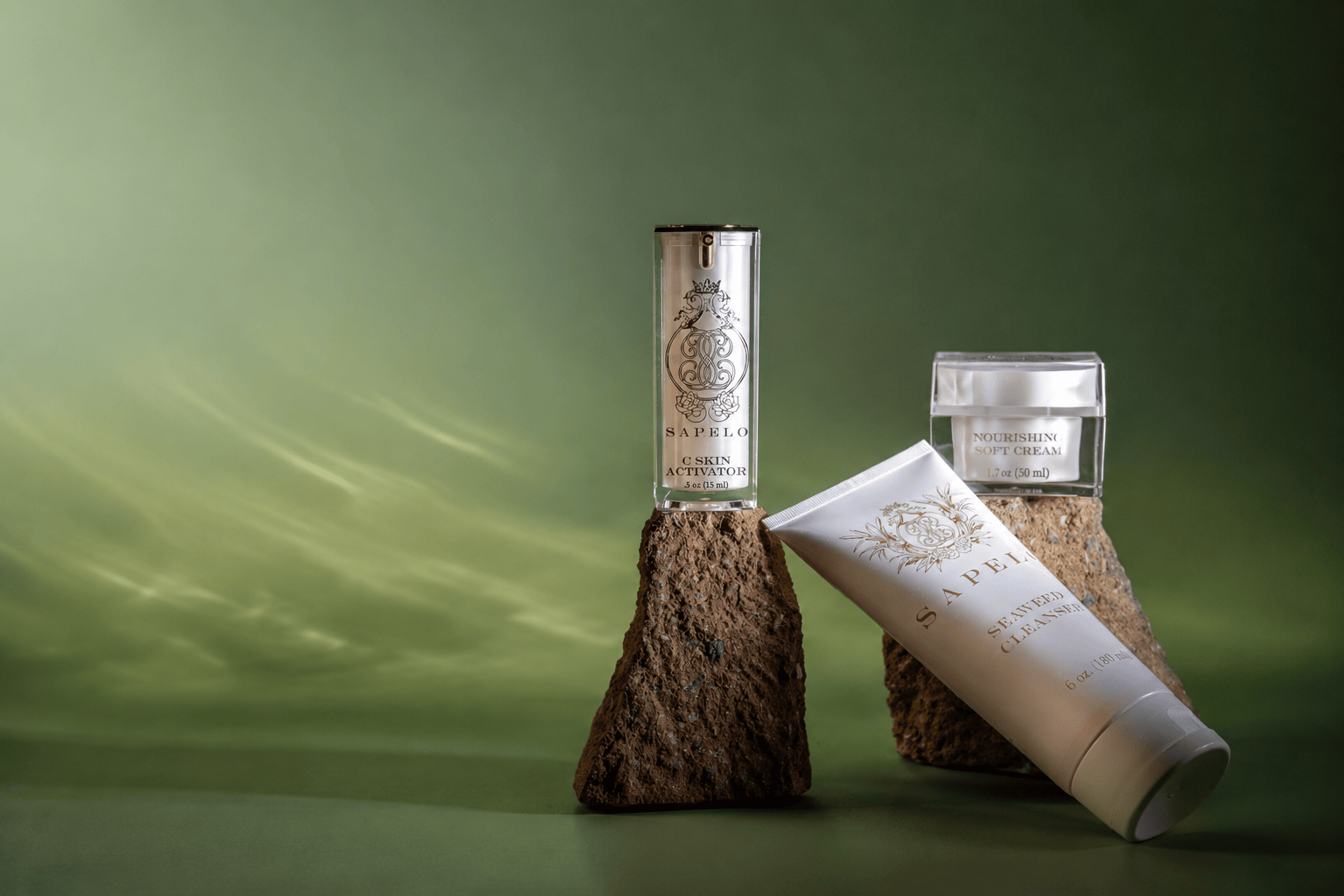 Three skincare products from Savvy Skin Care are displayed on textured brown bark stands against a dark olive green background. The products include a silver cylindrical bottle of Cica Gel, a white tube of Face Cream leaning on a bark stand, and a clear jar of Lip Balm with a white lid.